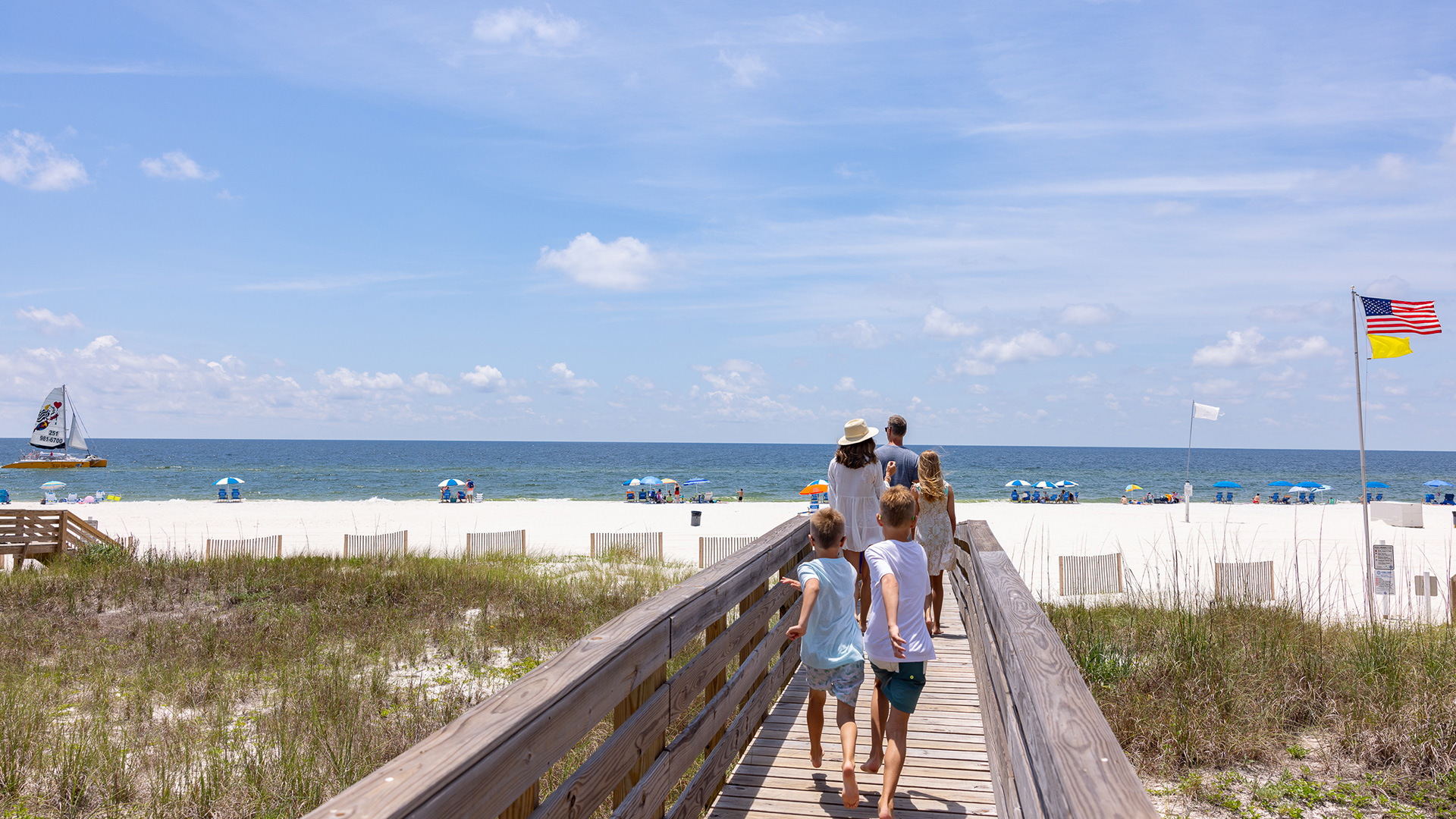 Una familia paseando por un malecón hacia la playa en Gulf Shores, Alabama