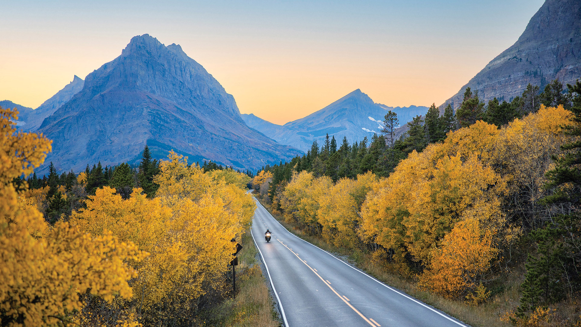 Faire de la moto à travers les couleurs d'automne et les paysages montagneux de Glacier National Park, Montana
