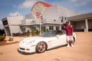 A man posing with a white Corvette at the National Corvette Museum in Bowling Green, Kentucky